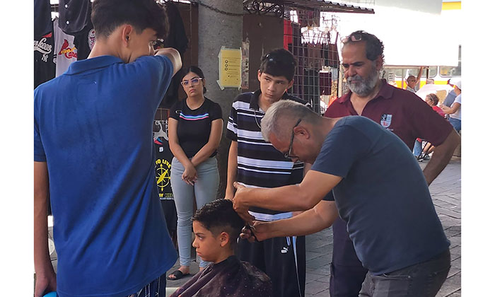Regalan cortes de cabello y útiles a niños en el andador del Mercado Municipal
